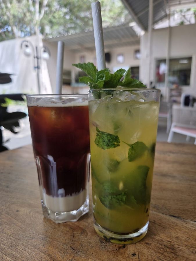 Dois copos altos, um de café gelado em camadas e outro de limonada com hortelã