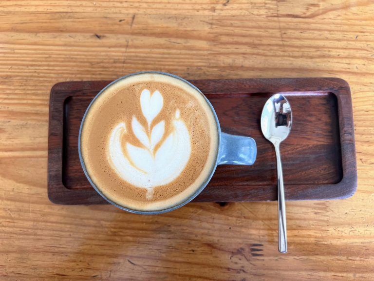 Latte com desenho de folha na espuma, servido em xícara azul